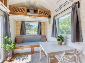 A cozy interior with a bench seating area, a table, and a window with curtains. - De Glamping - Tiny Safari Geel | 7p by Interhome (Zeewolde)