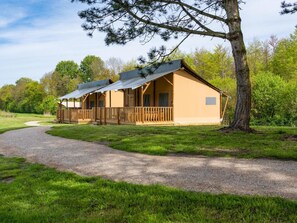 A two-story lodge with a covered porch and a gravel path leading to it. - De Glamping - Sunny Duo | 8p by Interhome (Zeewolde)