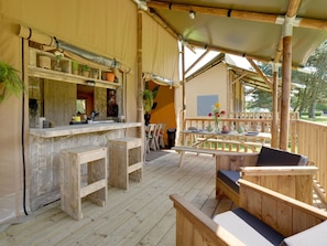 A wooden deck with a bar area, seating, and potted plants. - De Glamping - Sunny Duo | 8p by Interhome (Zeewolde)