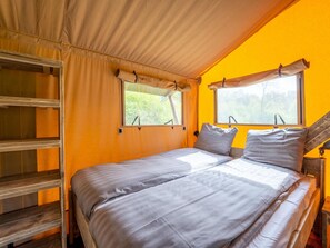 A single bed with a headboard, two windows, and a wooden shelf unit. - De Glamping - Sunny Duo | 8p by Interhome (Zeewolde)