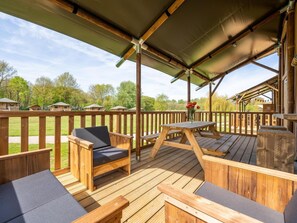 A wooden deck with outdoor seating and a covered area. - De Glamping - Sunny Duo | 8p by Interhome (Zeewolde)