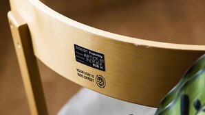A wooden chair with a label indicating it is a 'Frangly' design by 'Bob W.' and 'After 6' with '100% Offset' text. - Bob W Athens Stadiou (Athina)