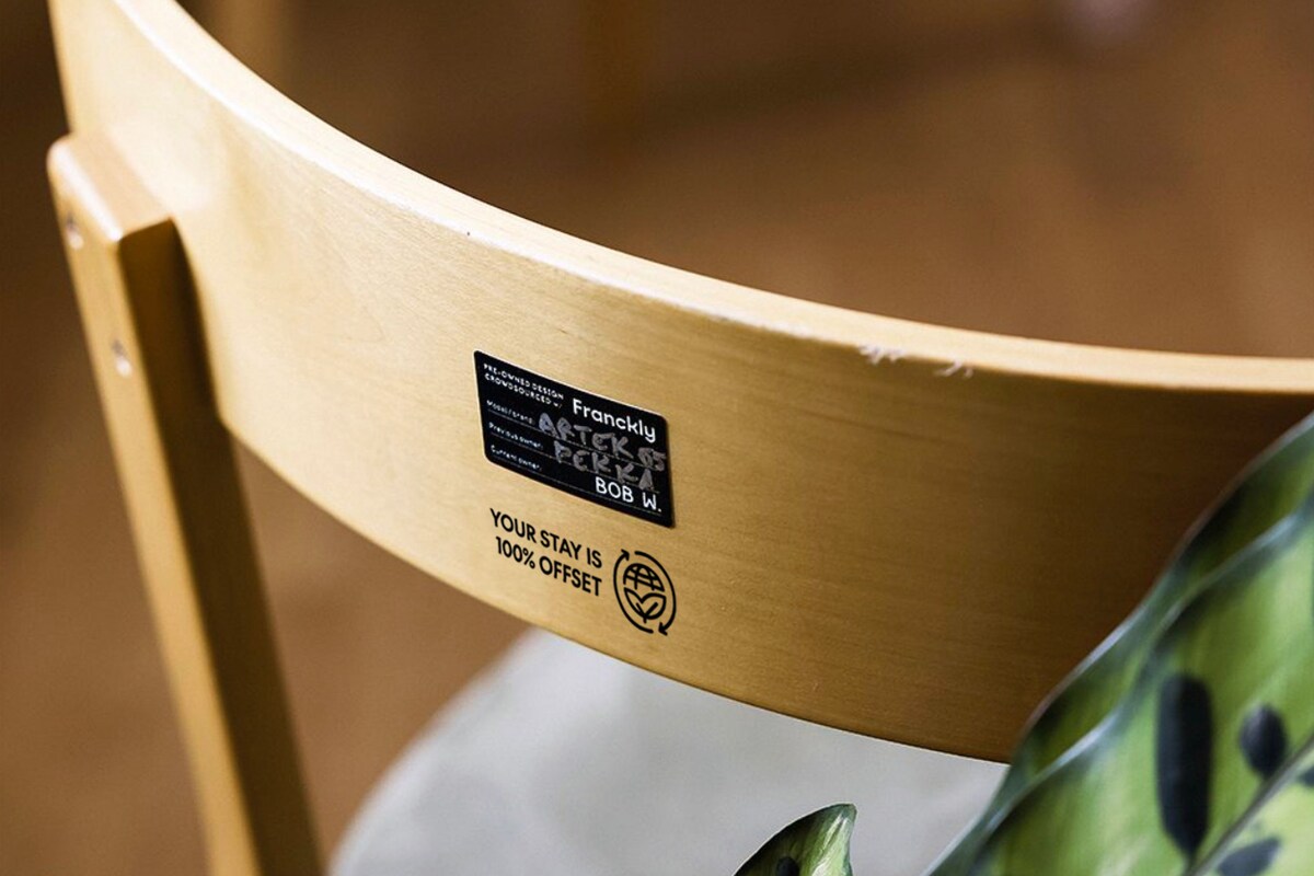 A wooden chair with a label indicating it is a 'Frangly' design by 'Bob W.' and 'After 6' with '100% Offset' text.