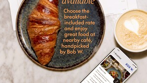 A croissant on a plate with a cup of coffee and a smartphone displaying a breakfast menu. - Bob W Athens Stadiou (Athina)