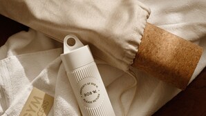 Eine weiße Wasserflasche mit Schriftzug, einem braunen Korken und einem weißen Handtuch mit Etikett.