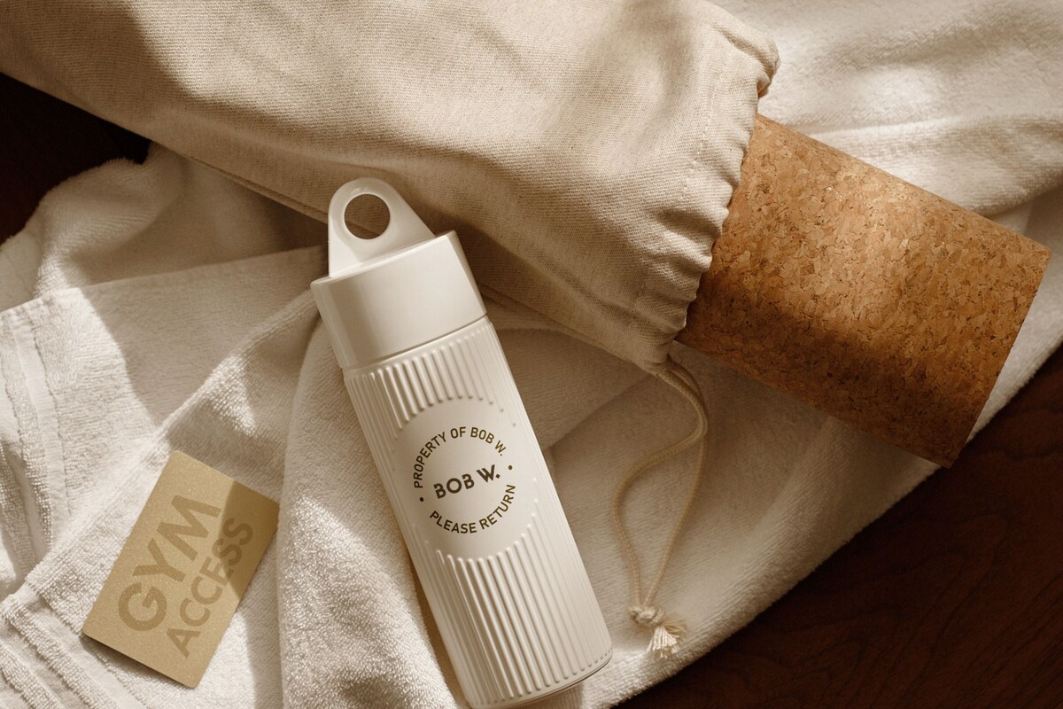 A white water bottle with text, a brown cork, and a white towel with a tag.