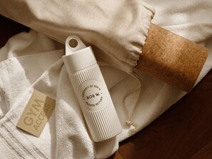A white water bottle with text, a brown cork, and a white towel with a tag. - Bob W Athens Stadiou (Athina)