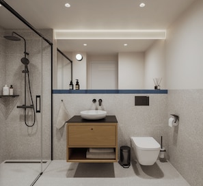 Un baño moderno con cabina de ducha de vidrio, un mueble de tocador de madera con lavabo blanco y un inodoro.