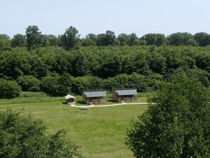 A rural property with two main buildings, one larger with a porch and the other smaller with a simple roof. - De Glamping - Sunny Trio | 14p by Interhome (Zeewolde)