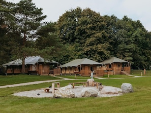 Un camping con yurtas, una mesa de picnic y una fogata.