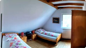 Un dormitorio pequeño y acogedor con techo inclinado, una cama individual, un escritorio y ventana que proporciona luz natural.