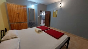 Un dormitorio con cama, un armario de madera, un espejo y una lámpara fijada a la pared.