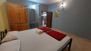 Een slaapkamer met een bed, een houten garderobe, een spiegel en een wandlamp.
