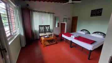 A room with a bed, a wooden table, a chair, and a window with curtains.