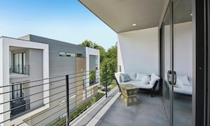 A modern balcony with a sofa and a table, overlooking a residential area.