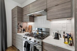 A modern kitchen with a gas stove, oven, and white tiled backsplash.