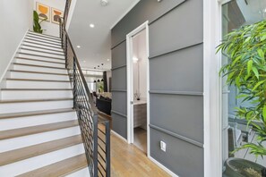 A staircase with a metal railing leading to a room with a gray wall and a wooden floor.