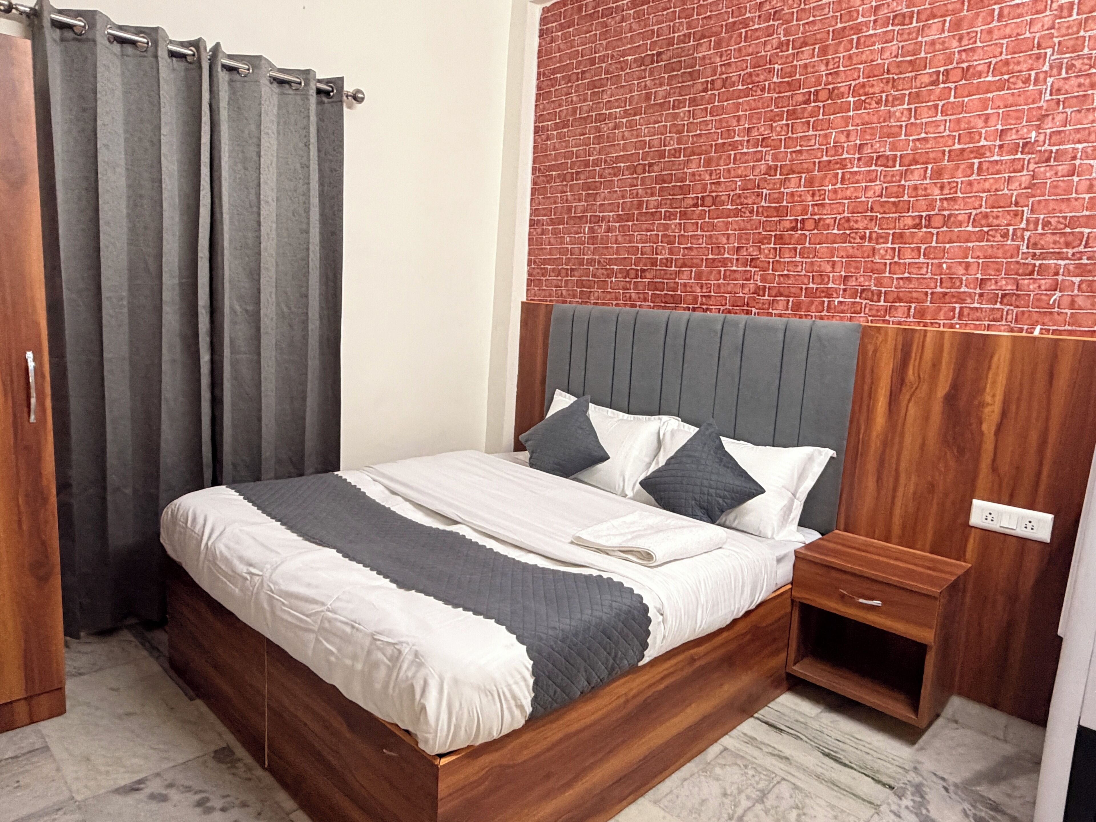 Un lit avec un cadre en bois, une literie grise et blanche, et une tête de lit grise.