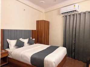 Habitación de hotel con cama, armario, aire acondicionado y cortina.