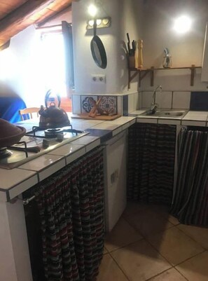 A compact kitchen with a stove, sink, and tiled backsplash.
