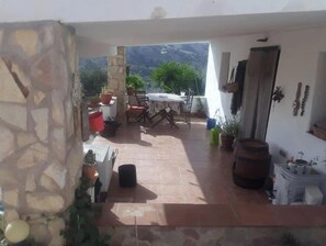 An outdoor patio area with a table and chairs, surrounded by potted plants and a stone wall.