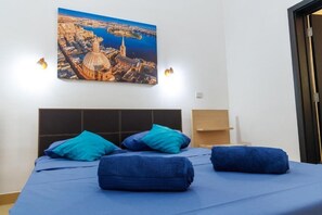Habitación de hotel con cama, almohadas, un cuadro colgado en la pared y lámparas de noche.