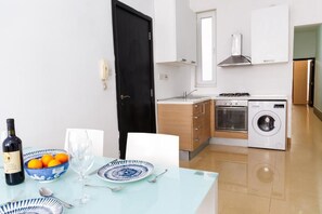 Cocina compacta con lavadora, estufa y lavabo.