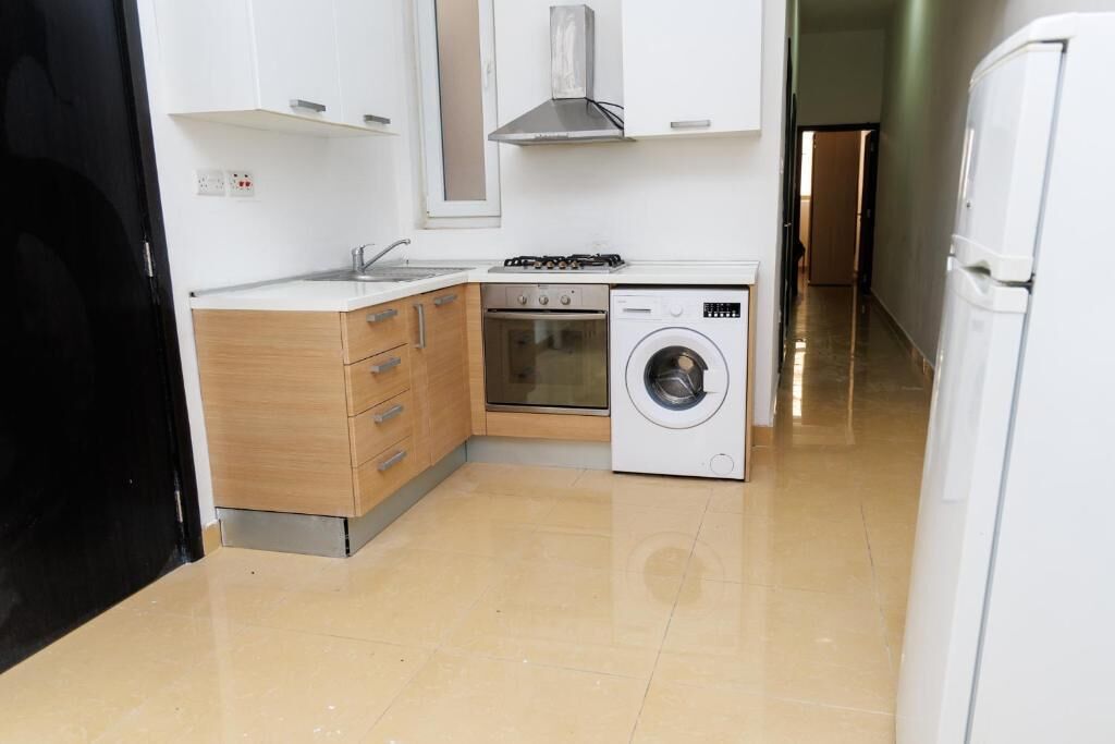 Une cuisine compacte équipée d’une cuisinière à gaz, d’un four, d’un lave-linge et d’un évier.
