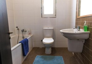 Un baño con bañera, inodoro, lavabo y ventana.