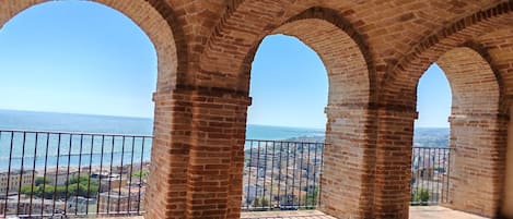 Un balcon orné d’arches en briques, d’où l’on peut admirer une vue sur le paysage urbain de la côte.