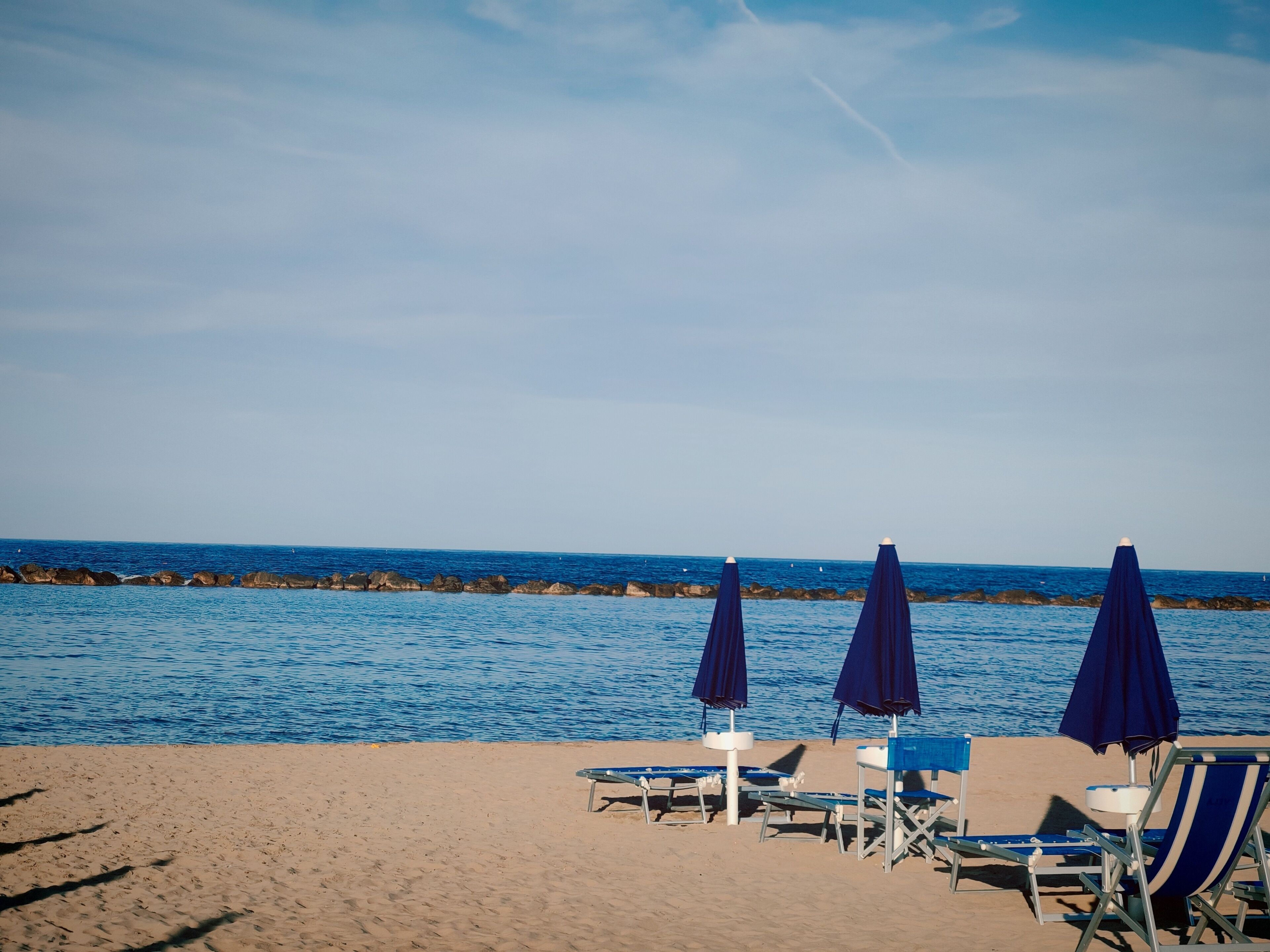 Ein Strand mit blauen Sonnenschirmen und Liegestühlen.