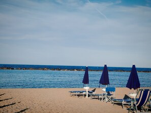 Une plage avec des parasols bleus et des chaises longues.