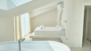 Quarto moderno com cama, um banco embutido e um claraboia.