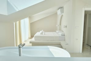 Une chambre moderne avec un lit, une banquette intégrée et une lucarne.