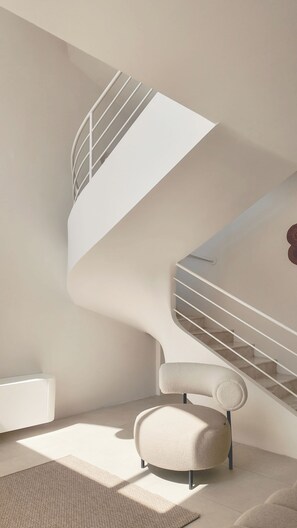 A modern interior with a spiral staircase, a round upholstered chair, and a radiator.
