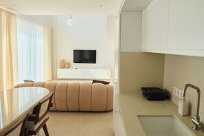 En moderne stue med et fladskærms-tv, et spisebord og en sofa.