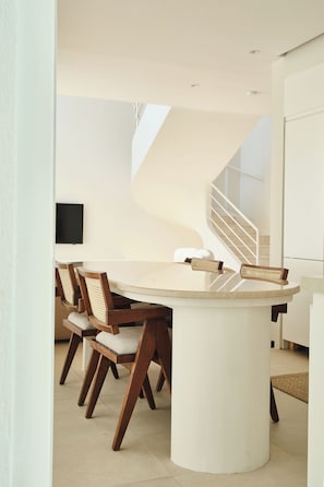 Un espace repas moderne avec une table ronde, des chaises en bois et un mur blanc.