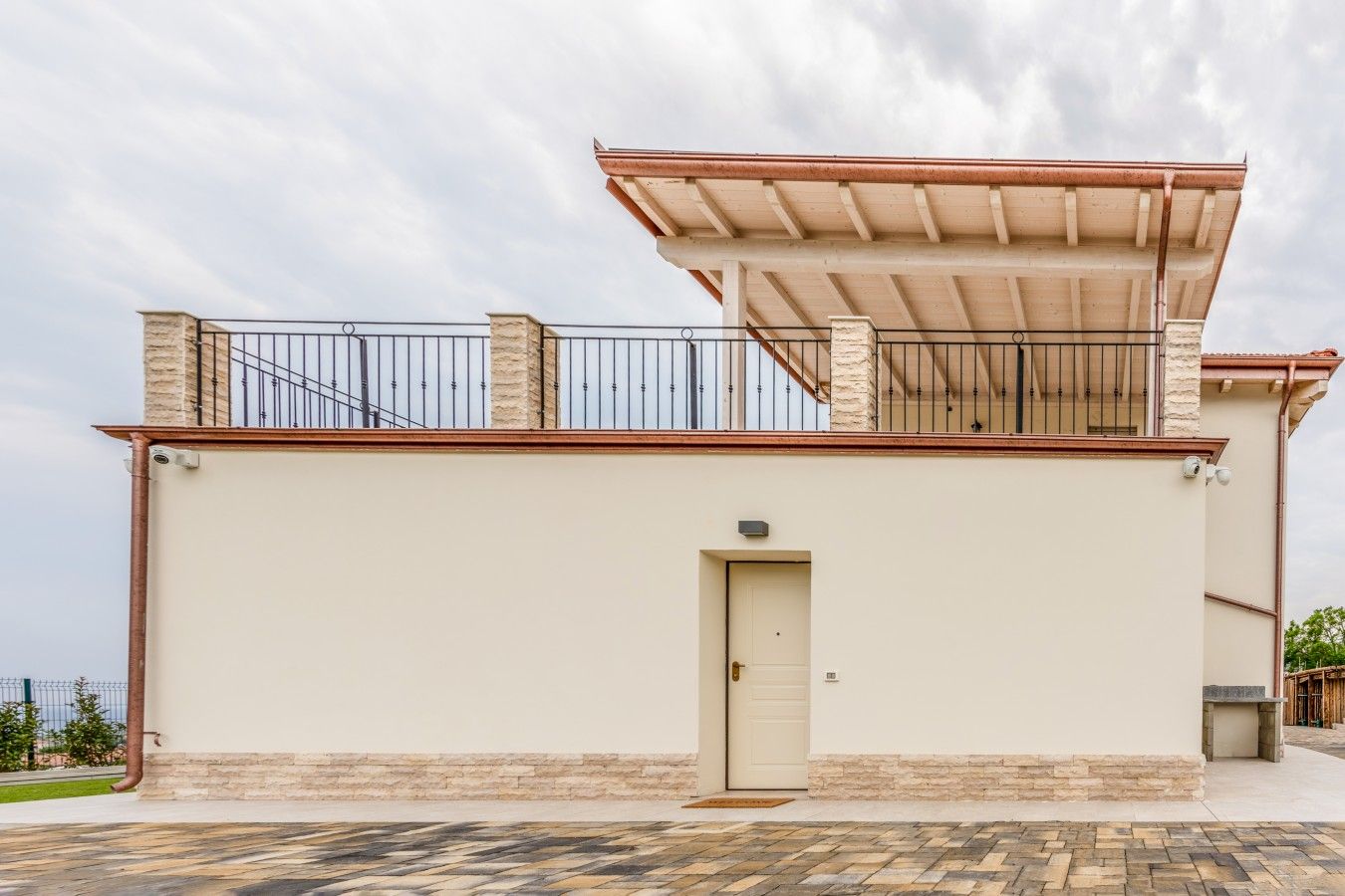 A building with a flat roof, a balcony with metal railings, and a door.