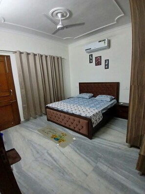 A bedroom with a bed, curtains, a ceiling fan, and an air conditioning unit. - Beautiful 3-BHK with Balcony in Sahibzada Ajit Singh Nagar Chandigarh Airport (Sahibzada Ajit Singh Nagar)