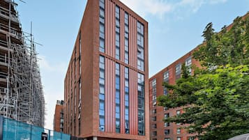 A modern high-rise building with multiple floors, large windows, and a brick facade.