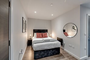 A modern bedroom with a bed, bedside tables, a round mirror, and a framed picture on the wall. - Host Stay Miller s Place Apartment (Liverpool)