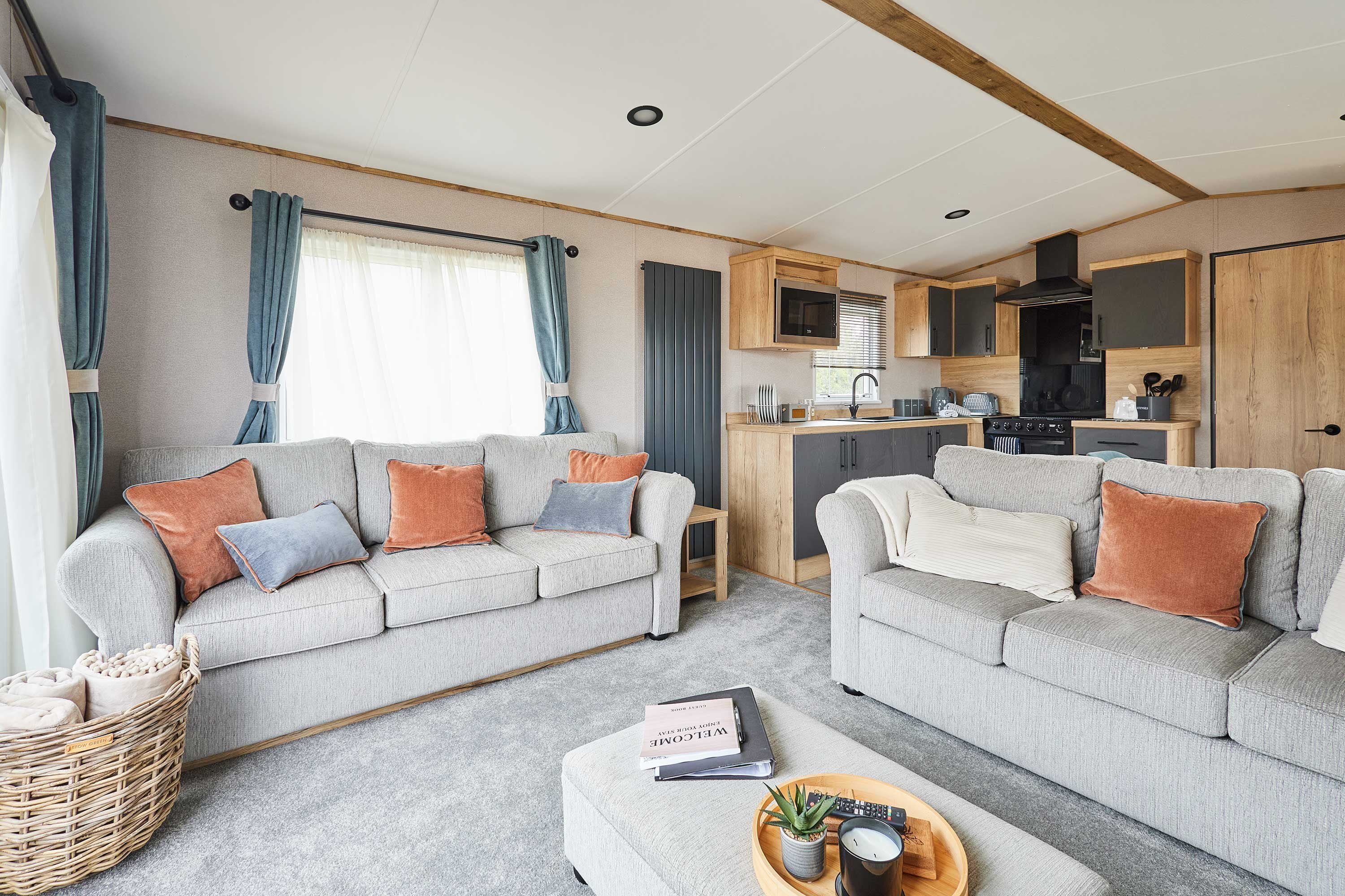 A cozy living room with two sofas, a small table, and a kitchen area with wooden cabinets and appliances.