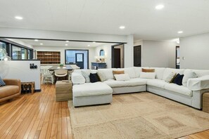 Ein modernes Wohnzimmer mit einer Eckcouch, einem Couchtisch und einem Essbereich mit Stühlen und einem Tisch.