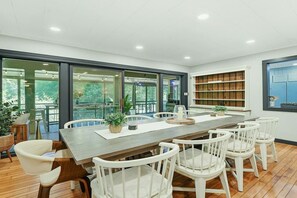 A dining area with a long table, white chairs, and a bookshelf. - Mountain Song-Hot Tub+Sauna+Arcade Gms+Fenced Yard (Maggie Valley)