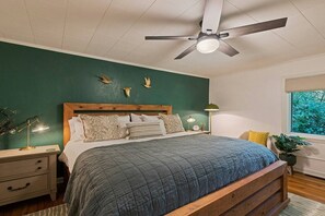 Ein Schlafzimmer mit einem Bett, Nachttischen, einem Deckenventilator und einem Fenster mit Blick.