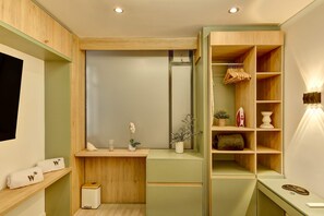Ein modernes Badezimmer mit Holzschränken, einem Waschtisch inklusive Spiegel und einer eingebauten Ablage mit Handtüchern und Pflegeprodukten.