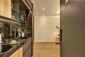 A modern kitchen with a black countertop, stainless steel appliances, and a marble backsplash. - w Charming 1BR in the Heart of Zona T (Bogotá)