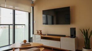 A modern living room with a flat-screen TV mounted on the wall, a wooden coffee table, a sofa, and a potted plant. - w Enchanting 1BR w Balcony in Prime Miraflores (Lima)