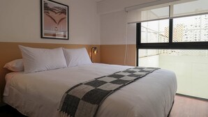 A hotel room with a bed, a wall-mounted picture, a window with a view, and a nightlight. - w Enchanting 1BR w Balcony in Prime Miraflores (Lima)