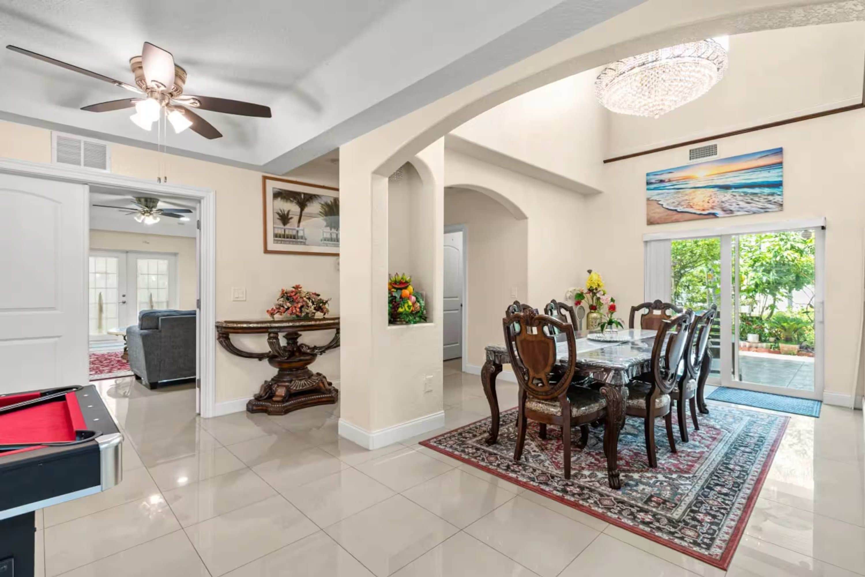 A dining area with a table and chairs, a ceiling fan, and a chandelier.